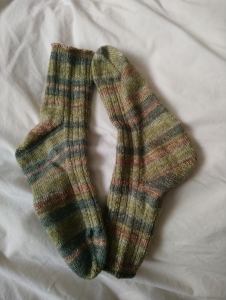 a pair of green striped socks laying flat on cream coloured fabric